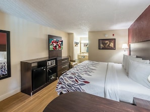 Een hotelkamer met een bed, een aan de muur bevestigde televisie, een bureau en een kast.