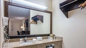 Ein Badezimmer mit großem Spiegel, Waschbecken, Handtuchhalter und Föhn.