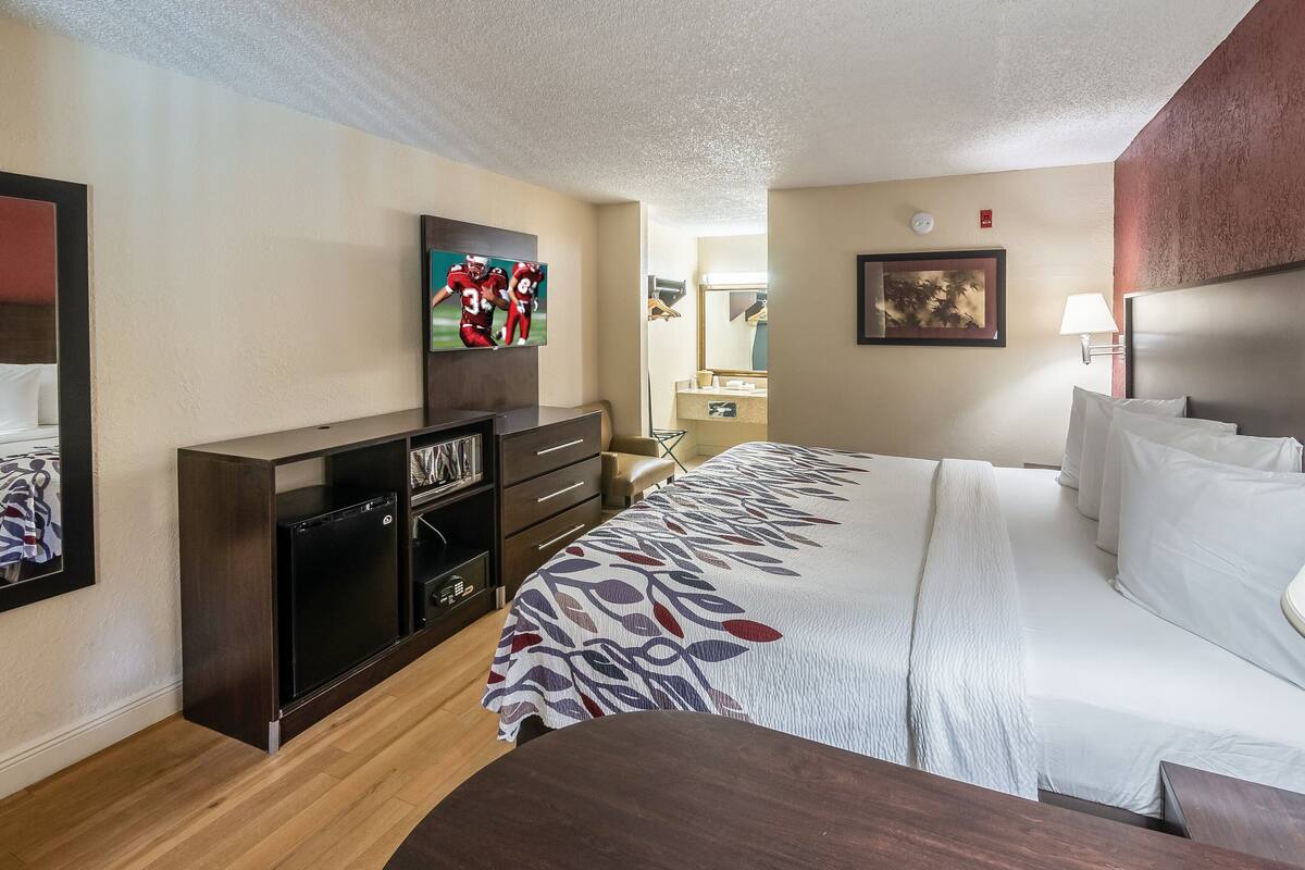Una habitación de hotel con cama, televisión, escritorio y cómoda.