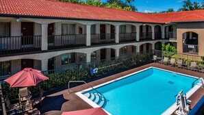 Ein Hotel mit Schwimmbad, Außenbereich und einem roten Ziegeldach.