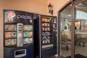 Twee automaten, één voor Pepsi en een andere met diverse snacks, naast de ingang van een gebouw.