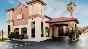 A Red Roof Inn with a parking lot, a covered entrance, and a palm tree.