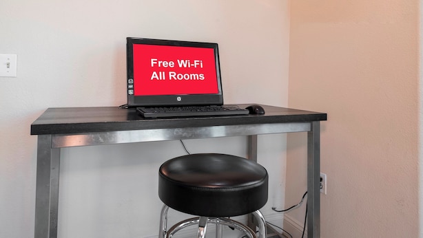 A laptop on a table with a sign indicating free Wi-Fi availability.