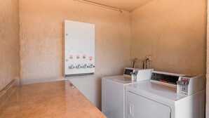 Un cuarto de lavandería con lavadora, secadora y un panel de control con varios botones.