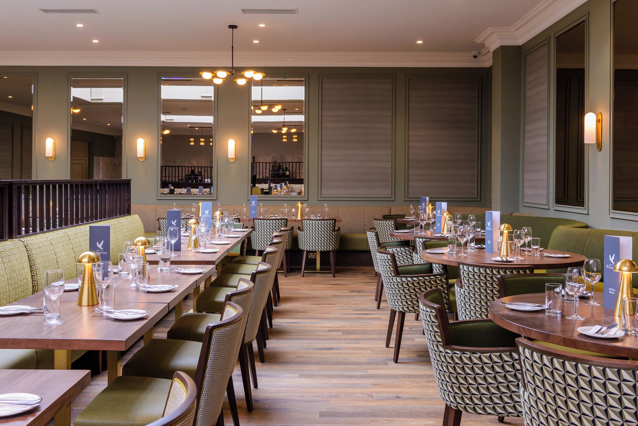 Um restaurante com mesas de madeira compridas, cadeiras estampadas e decoração de interiores moderna.