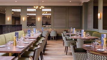 Um restaurante com mesas de madeira compridas, cadeiras estampadas e decoração de interiores moderna.