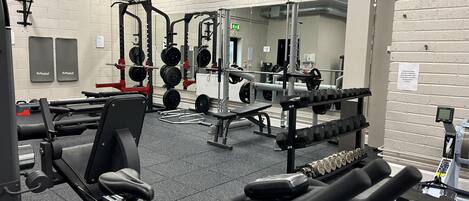 A gym with various exercise equipment, including weight machines, free weights, and cardio machines.