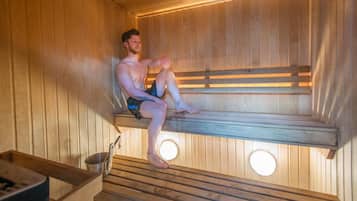 A sauna with wooden benches and a metal bucket.