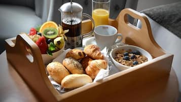Un plateau de petit-déjeuner avec des croissants, des fruits, du café, du jus et des céréales.