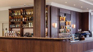 A bar area with wooden paneling, shelves stocked with bottles, and a coffee machine. - Hotel Killarney (Killarney)