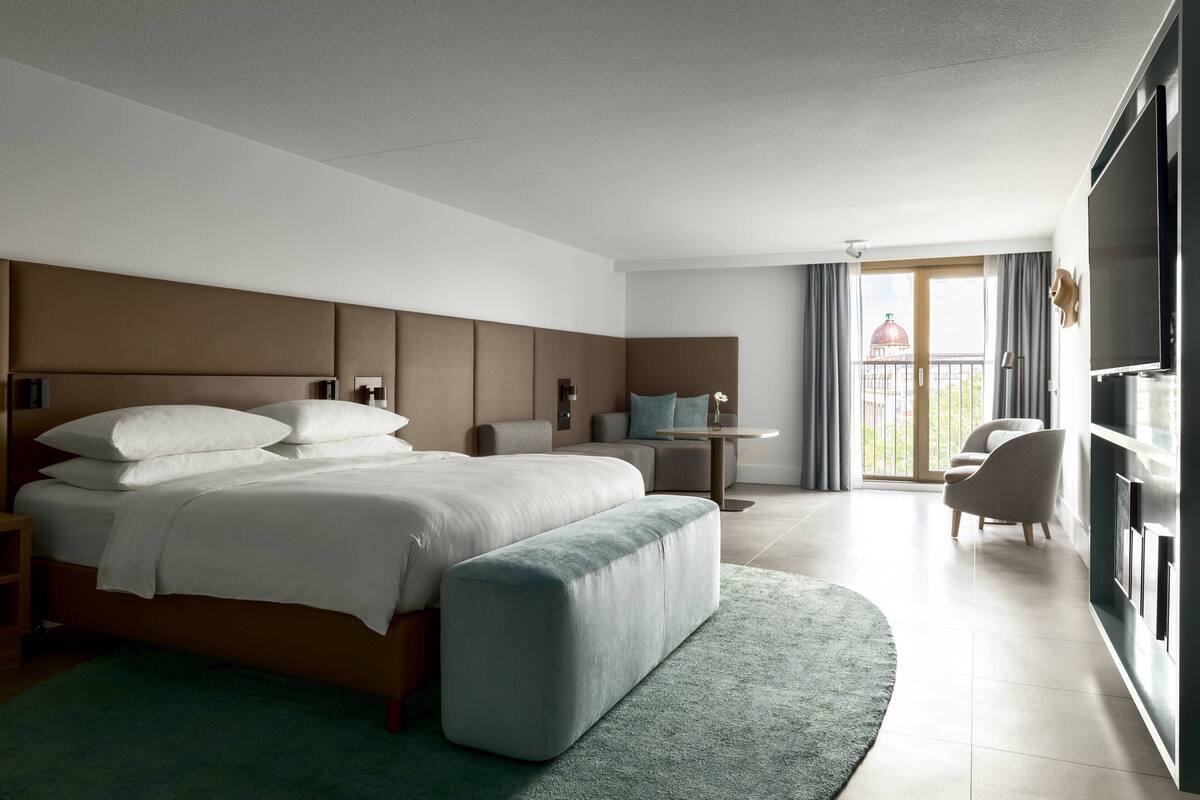 Une chambre d’hôtel moderne dotée d’un grand lit, d’un coin salon et d’un balcon avec vue.