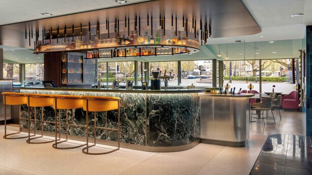 Un área de bar moderna con encimera de mármol, taburetes y una lámpara colgante llamativa.