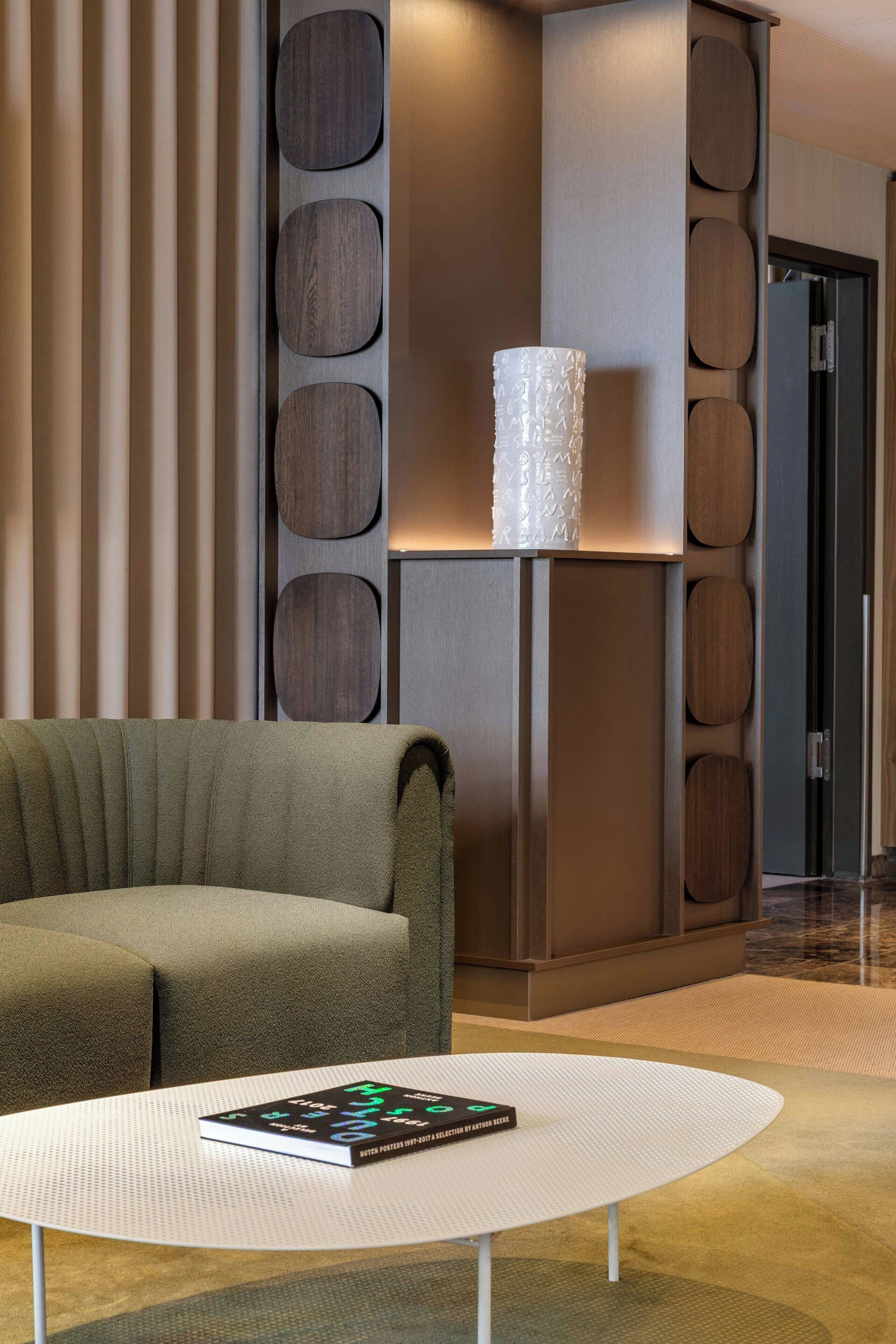 Un intérieur moderne avec un canapé, une table ronde blanche et un mur décoratif orné de motifs circulaires.