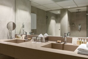 A modern bathroom with two sinks, a large mirror, and various toiletries.