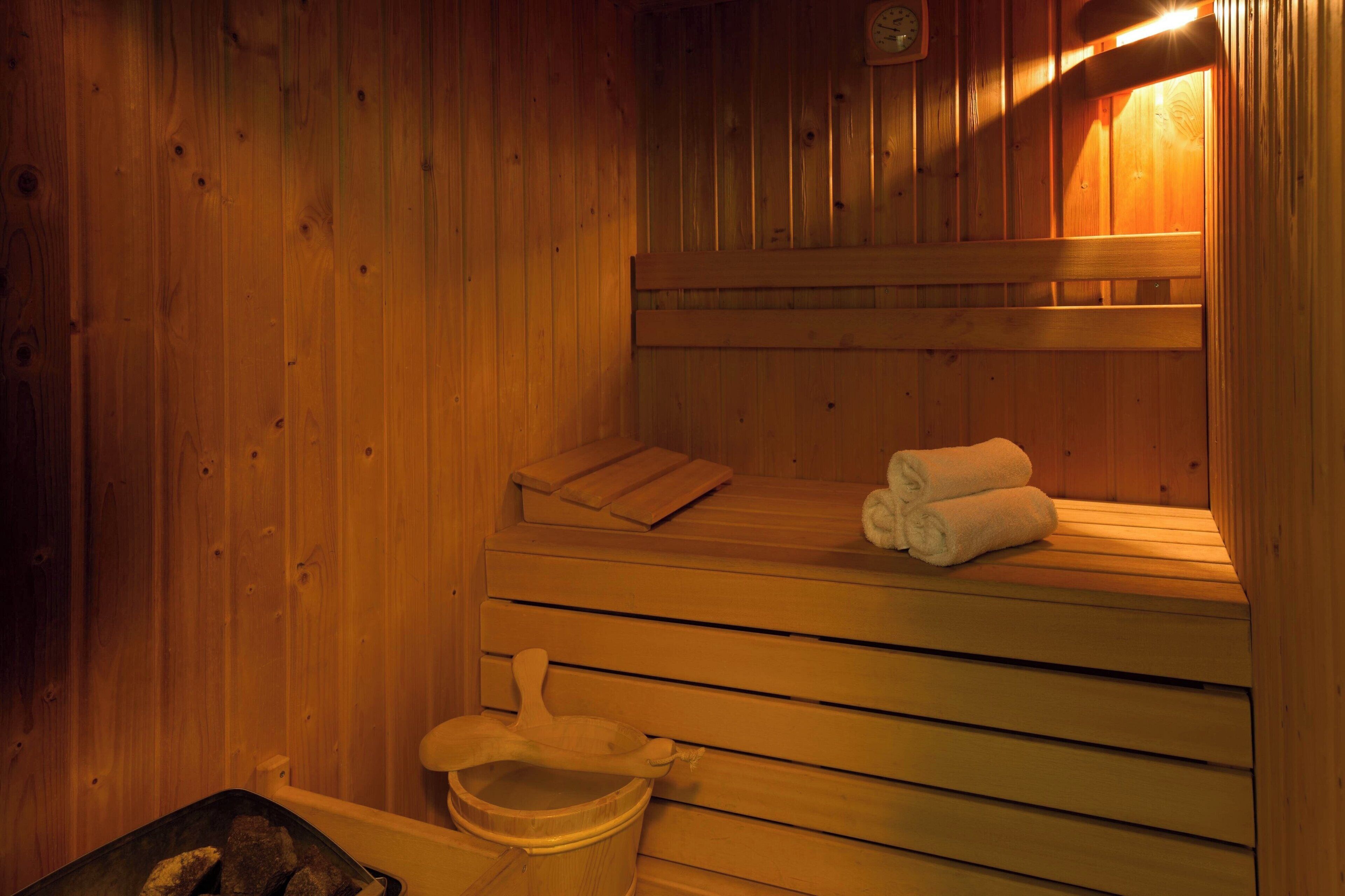 A wooden sauna with benches, a bench heater, and towels.