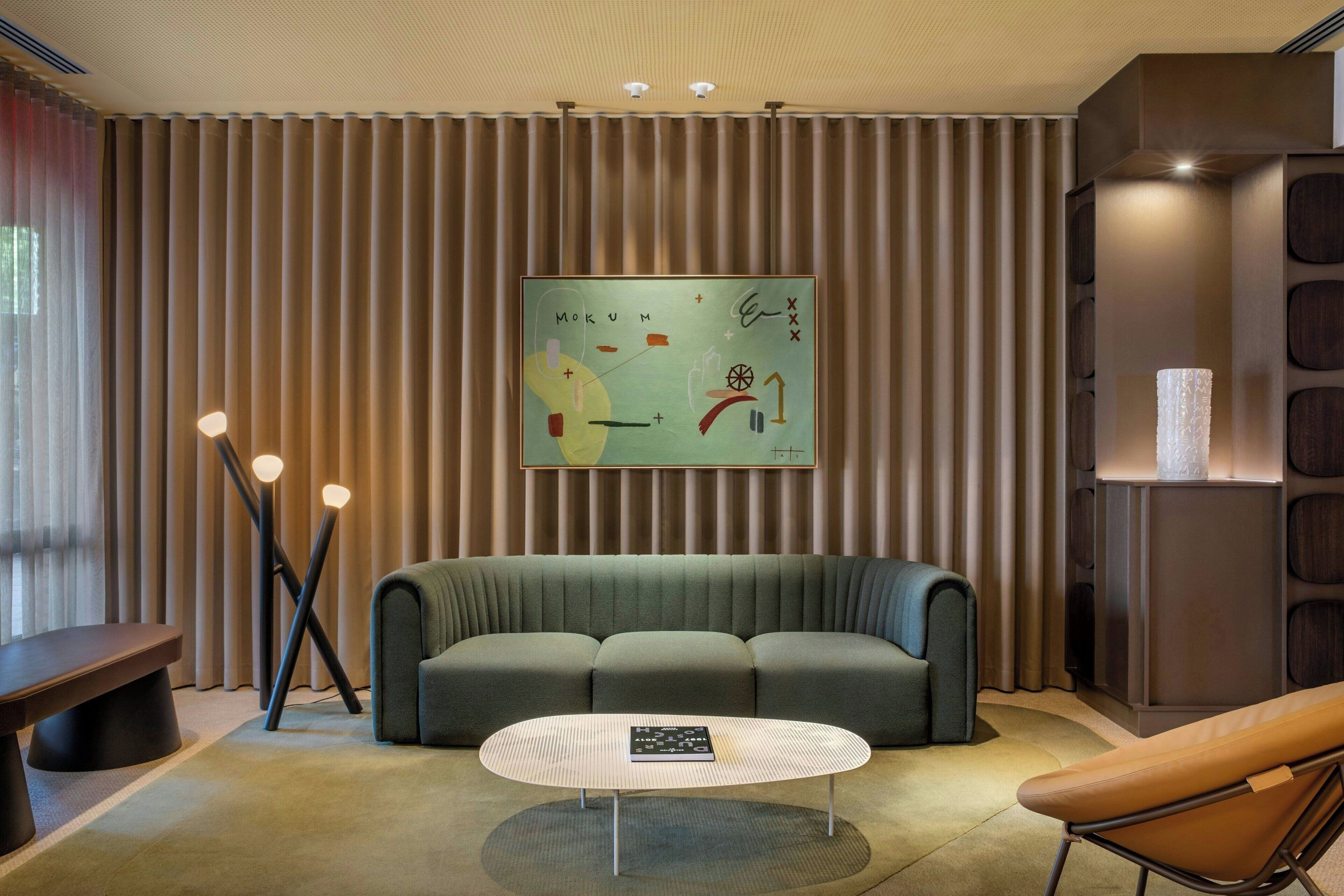 Un salon moderne avec un canapé vert, une table basse ronde et un tableau abstrait accroché au mur.