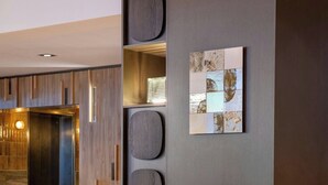 Un vestíbulo moderno con un sillón de cuero redondo, una pequeña mesa de madera y una obra de arte colgada en la pared.