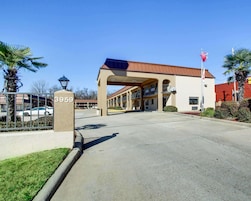 A hotel entrance with a numbered sign, a covered walkway, and a flag.