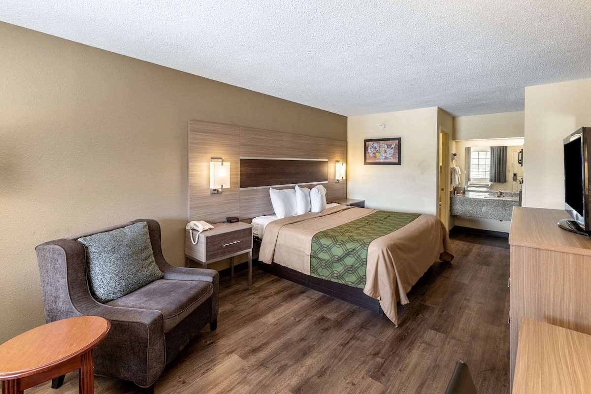 A hotel room with a bed, a sofa, a desk, and a television.