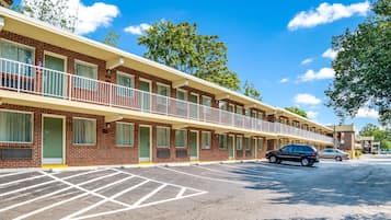 A motel with a brick facade, multiple balconies, and a parking lot.