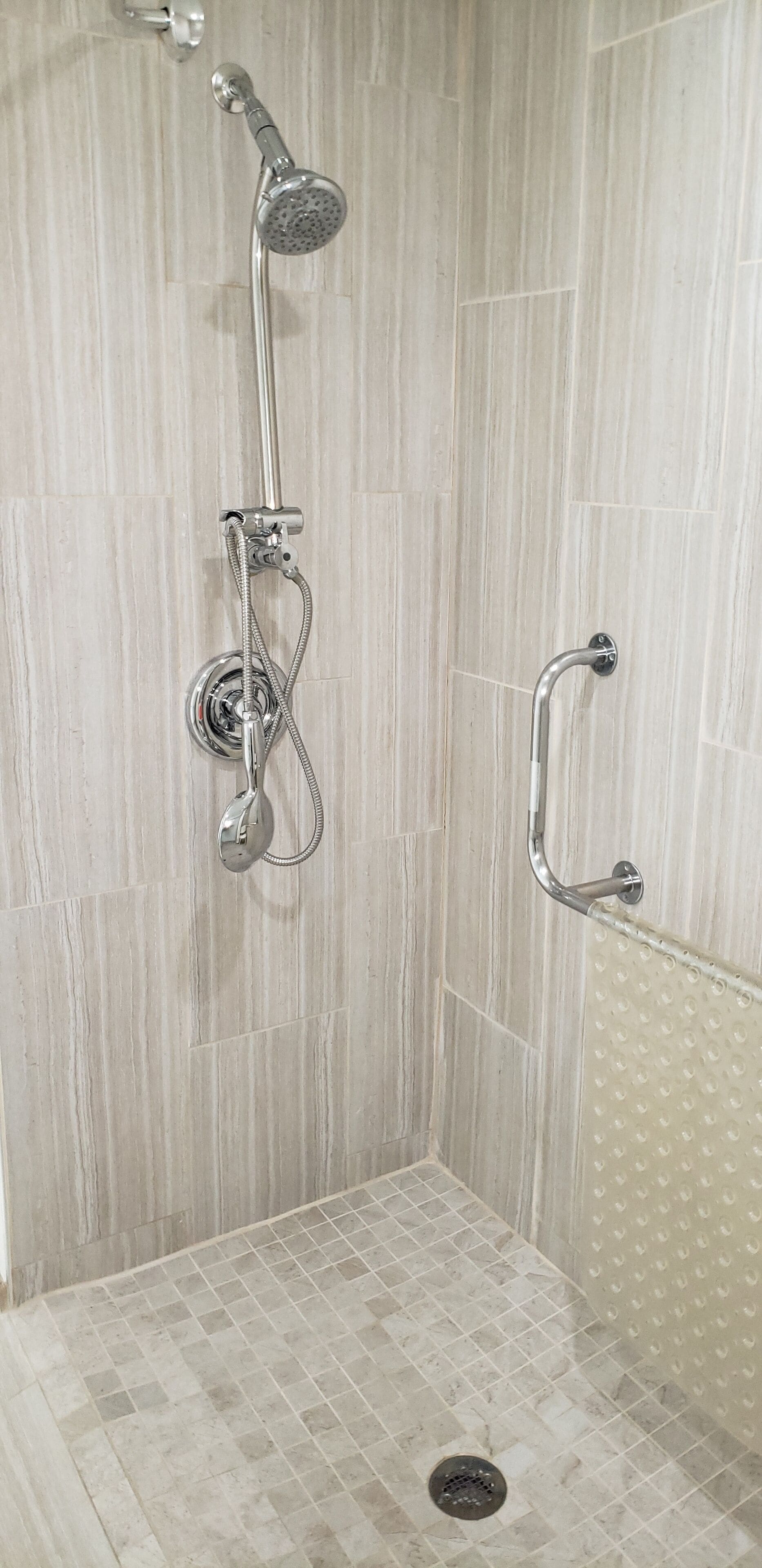 A shower with a handheld showerhead and a handheld shower attachment.
