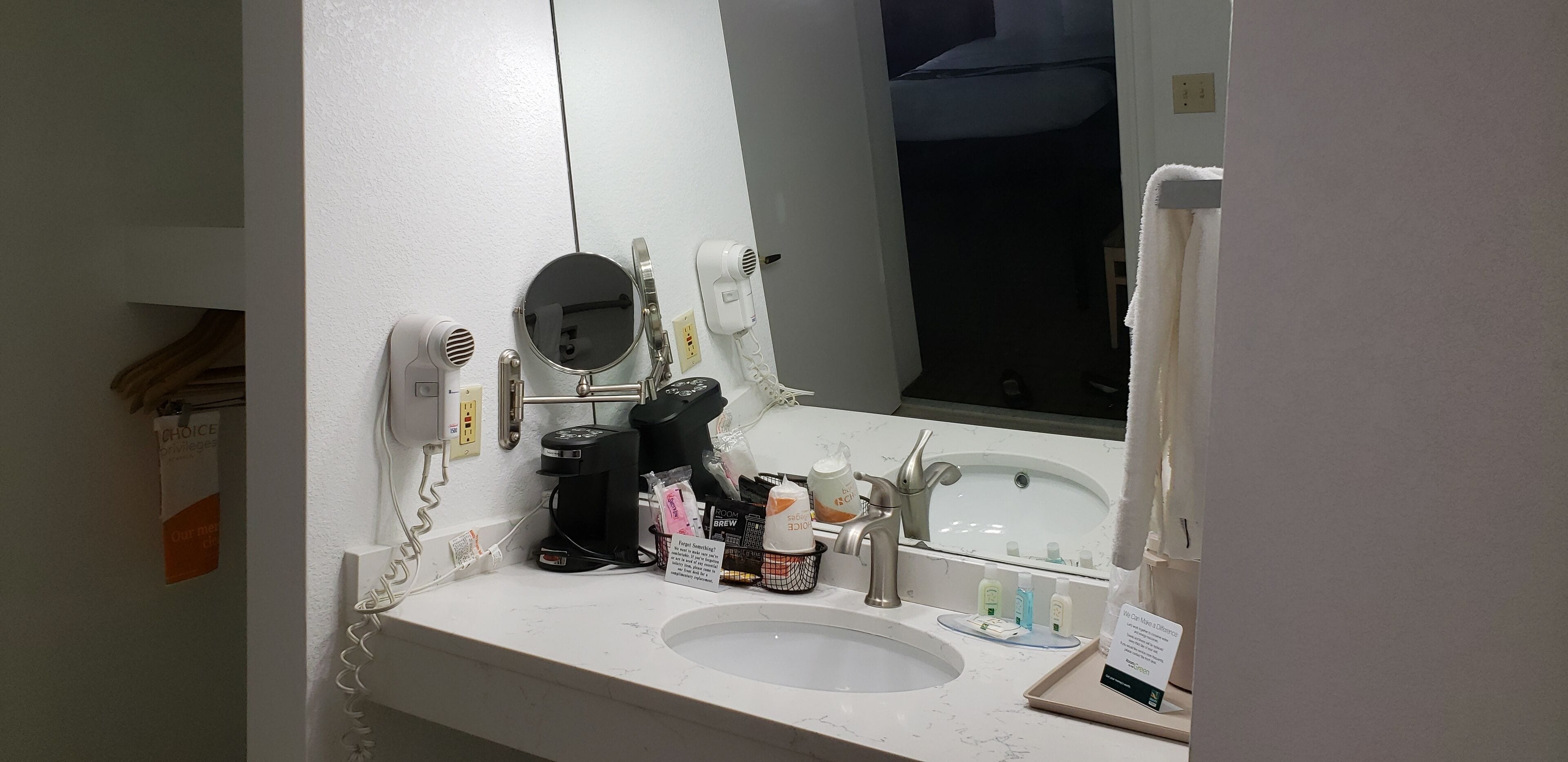 Ein Hotelbad mit Waschbecken, Spiegel, Föhn und Kaffeemaschine.