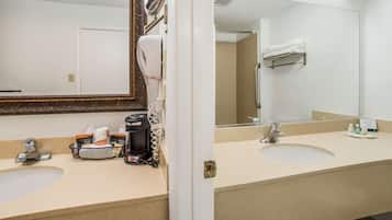 Un baño de hotel con dos lavamanos, un espejo grande, un secador de pelo y un perchero para toallas.