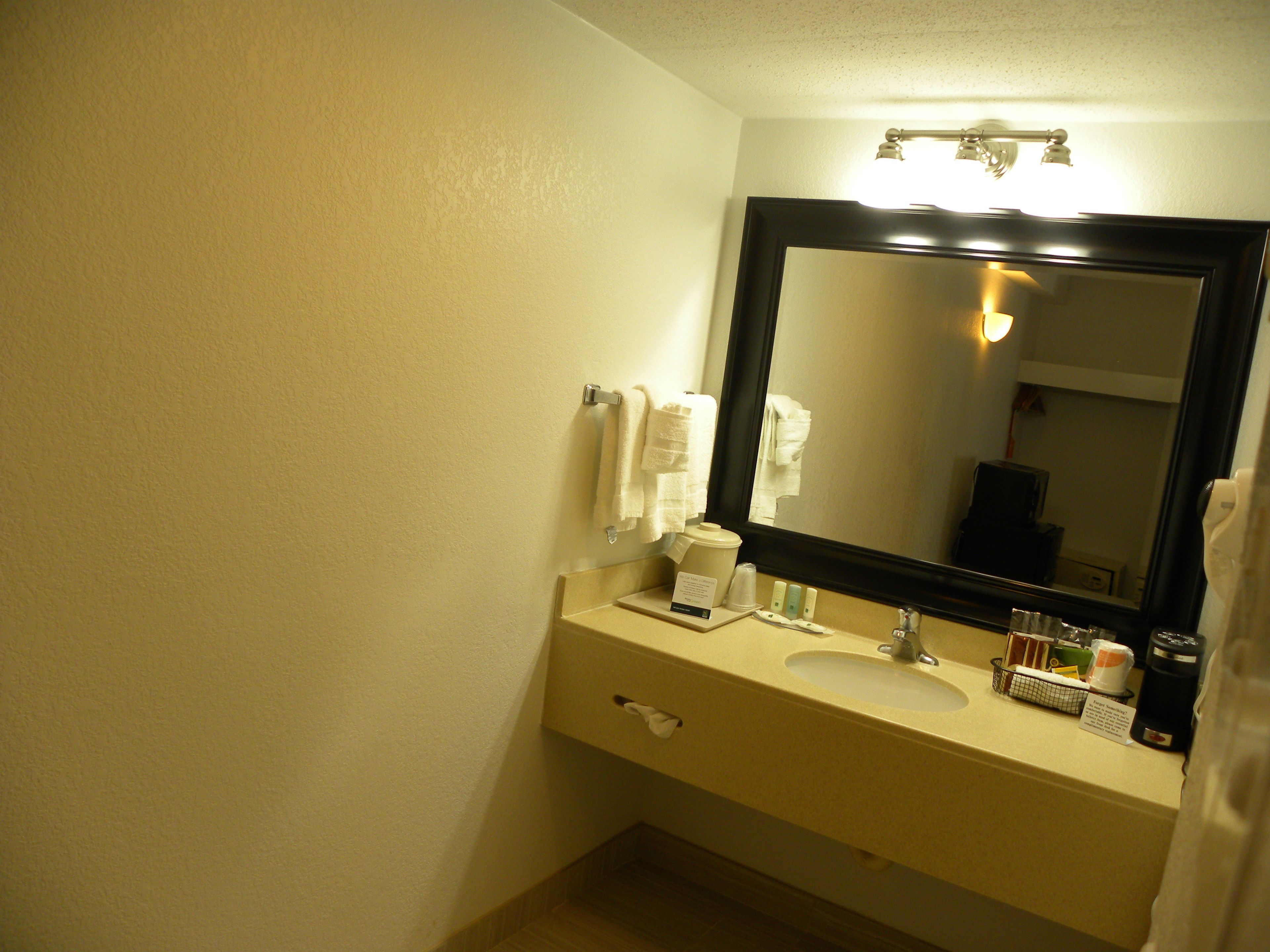 Une salle de bain équipée d’un lavabo, d’un miroir, d’un porte-serviettes et d’articles de toilette.