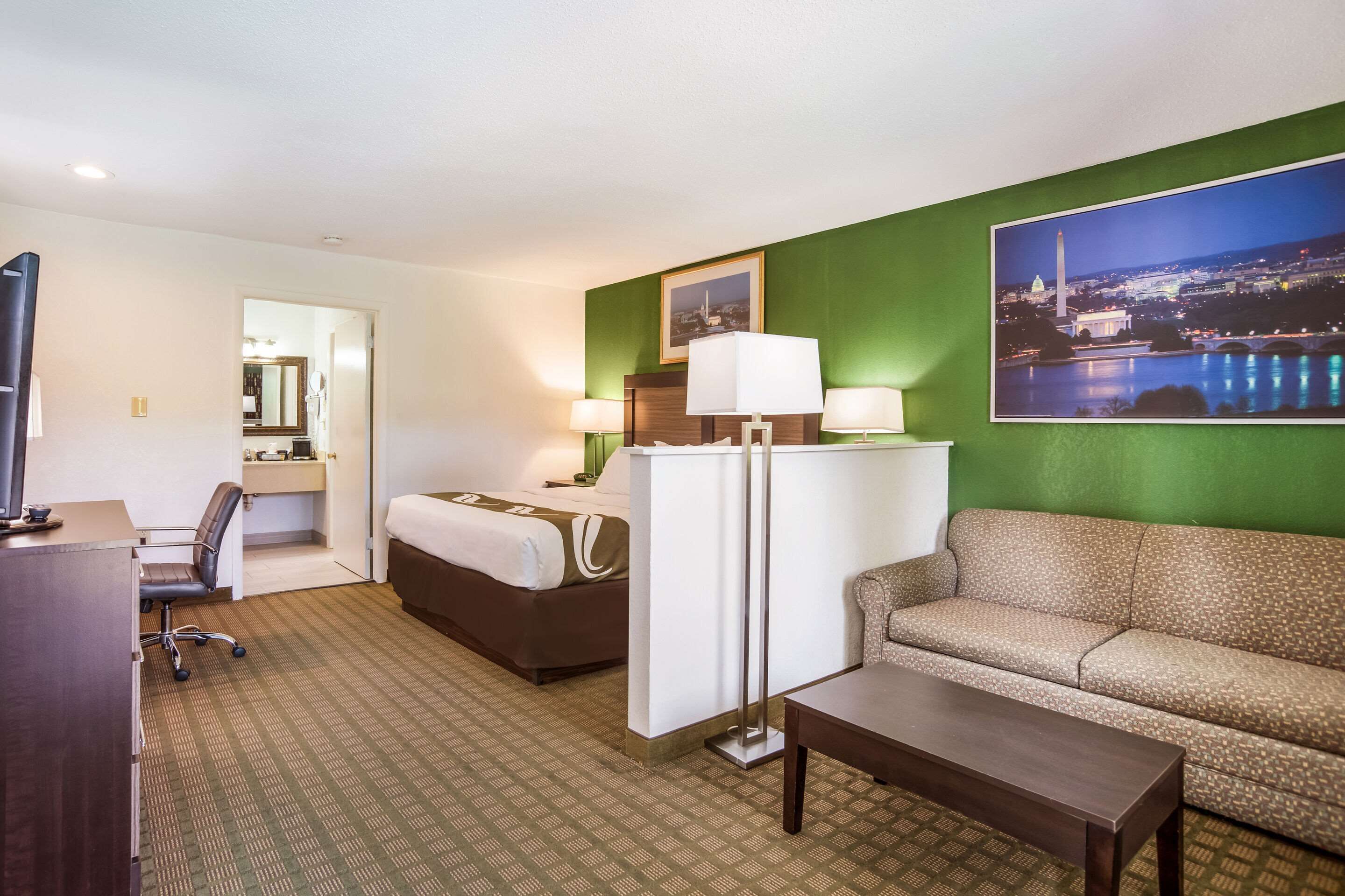 Una habitación de hotel con cama, sofá, escritorio y televisor.