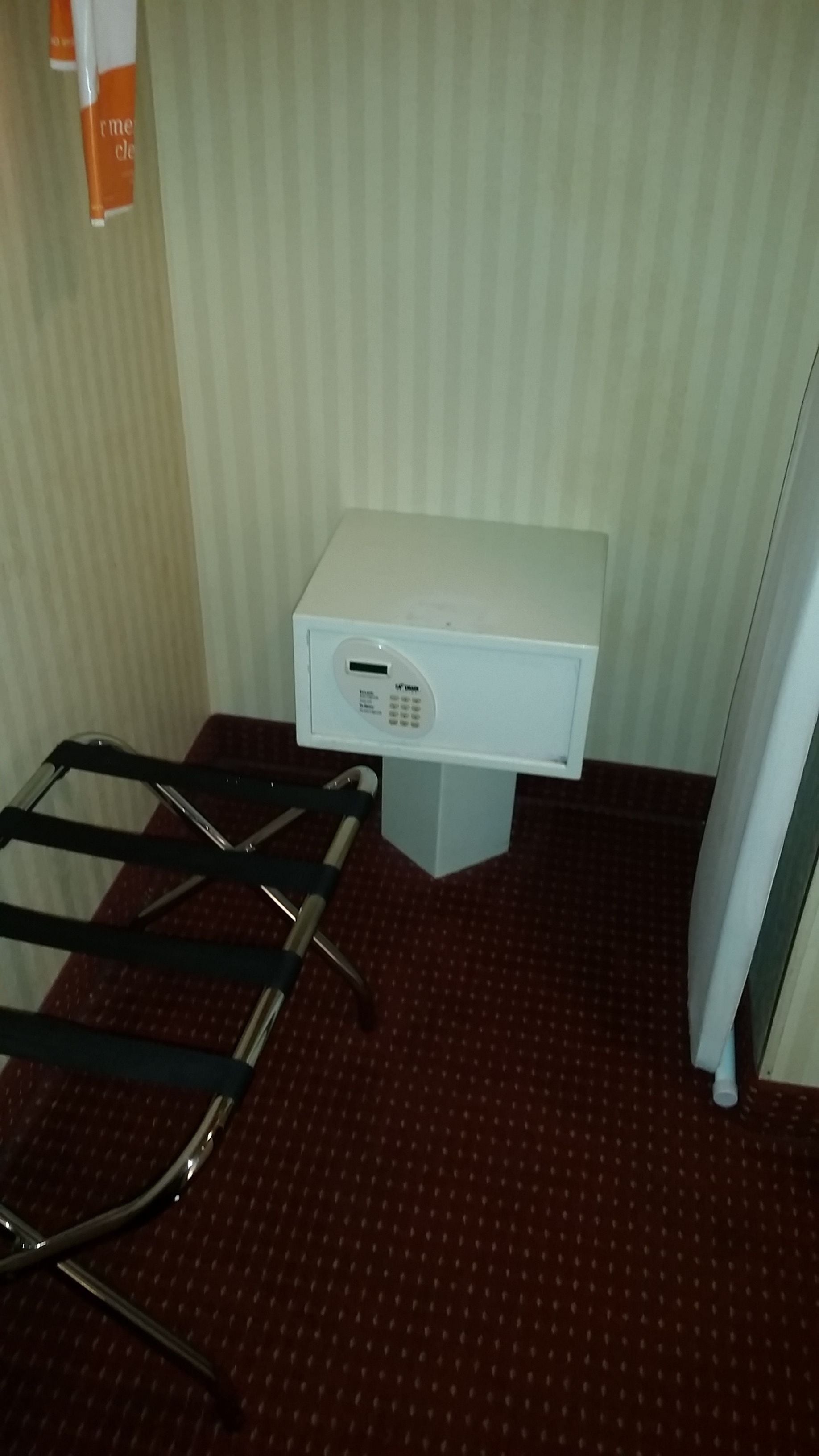 Une petite pièce avec un bureau blanc, une chaise, un radiateur et un mur à rayures.
