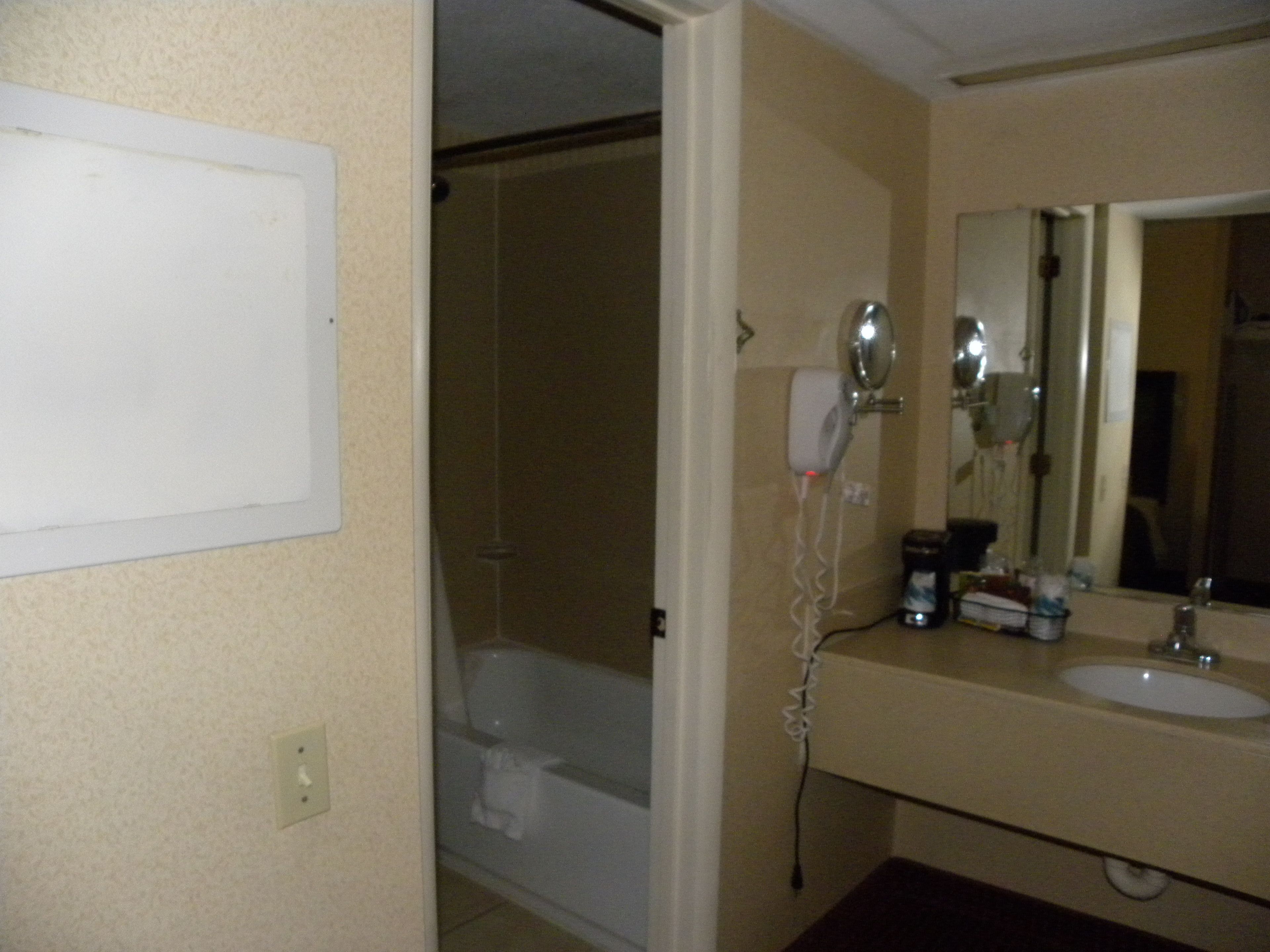 A bathroom with a sink, mirror, and a hairdryer on the counter.
