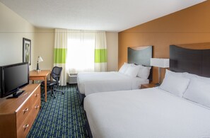 A hotel room with two beds, a desk with a computer, a chair, and a television.
