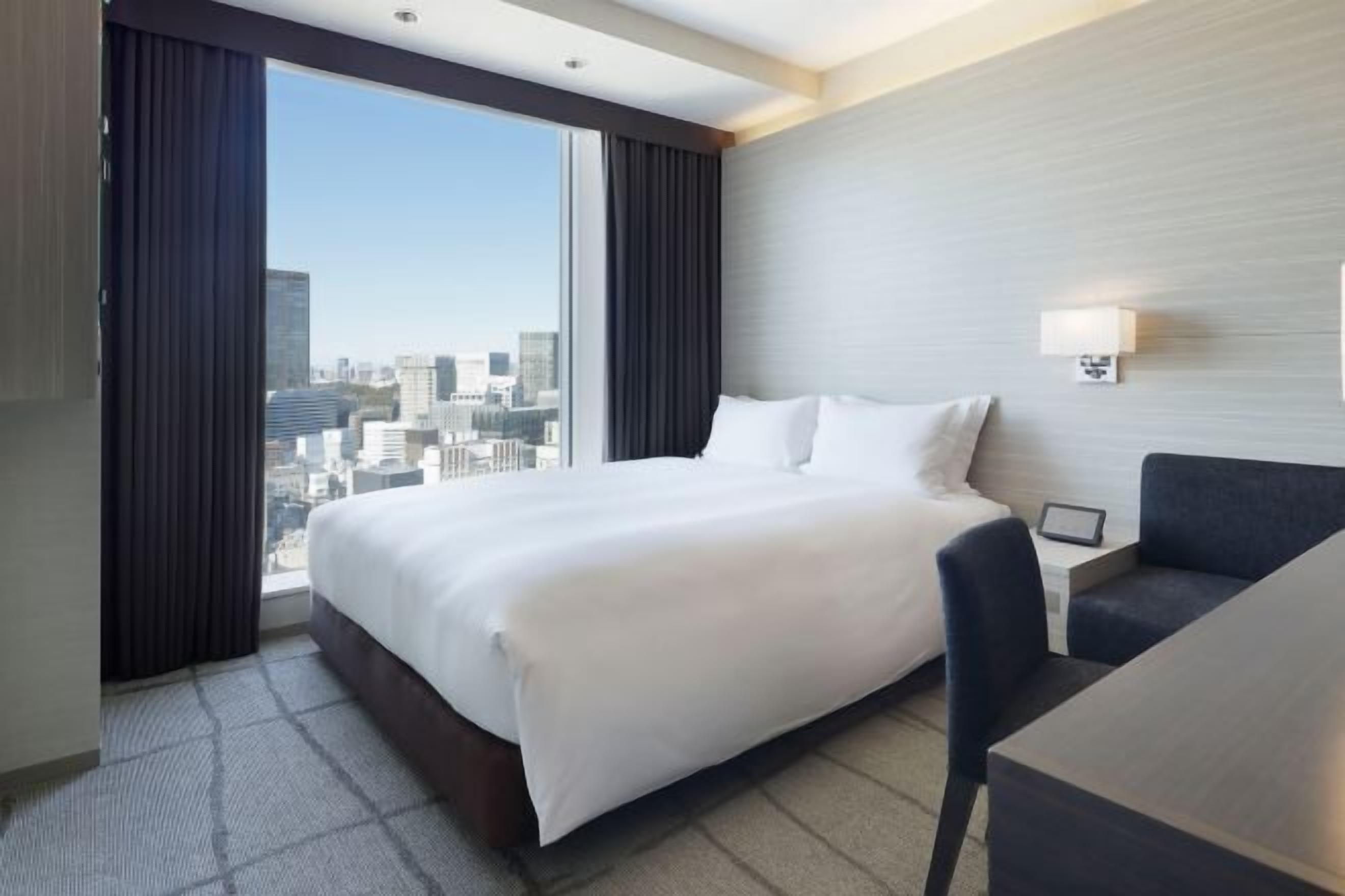 A hotel room with a large bed, a desk, and a view of the city.