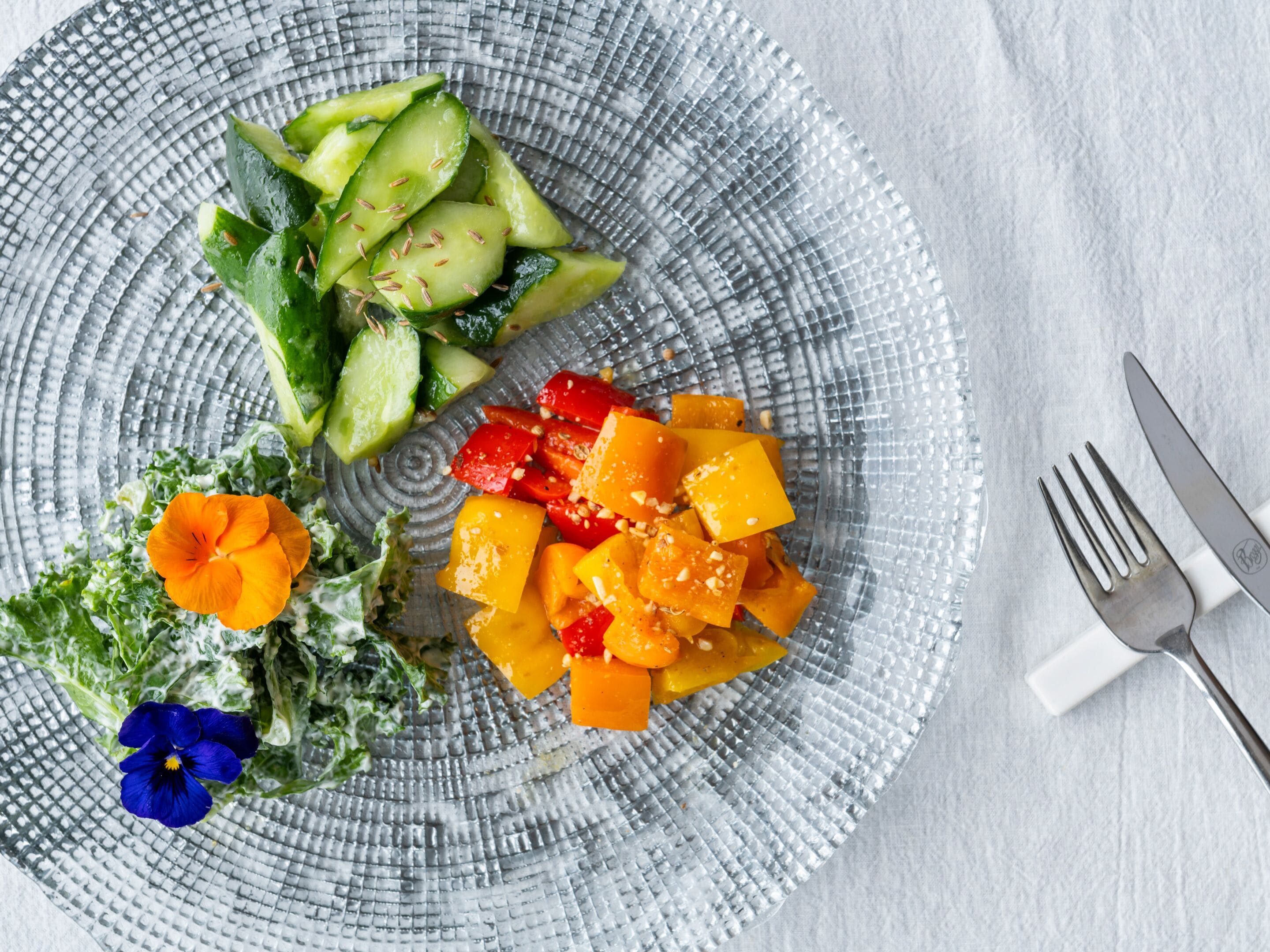 A plate with sliced cucumbers, diced mango, and a flower.