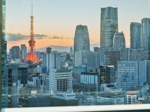 A cityscape with modern high-rise buildings, a prominent tower with red illumination, and a clear sky.