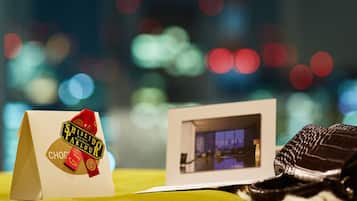 A gift bag with a chocolate label, a photograph of a room, and a chocolate bar on a yellow surface.