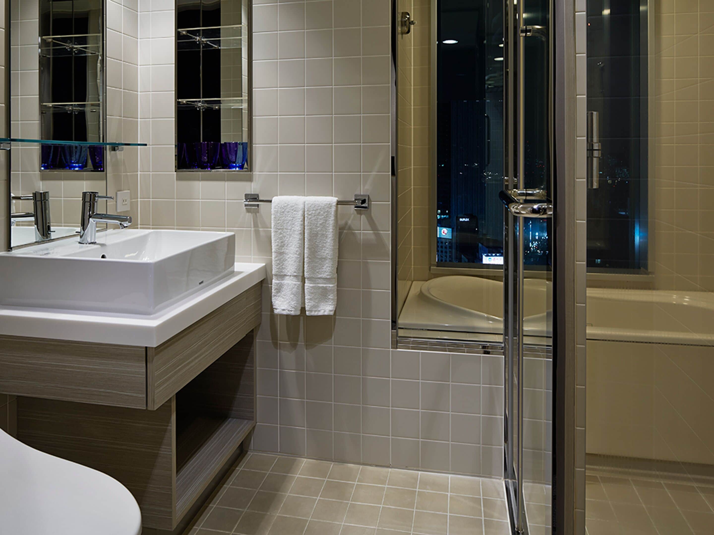 Un baño moderno con un lavabo grande, un espejo y una ducha con cerramiento de vidrio.