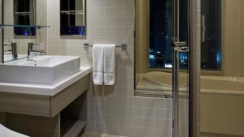A modern bathroom with a large sink, mirror, and a glass-enclosed shower.