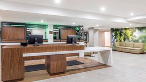 Un comptoir d’accueil doté de deux écrans d’ordinateur, d’un plan de travail en bois et d’un banc blanc.