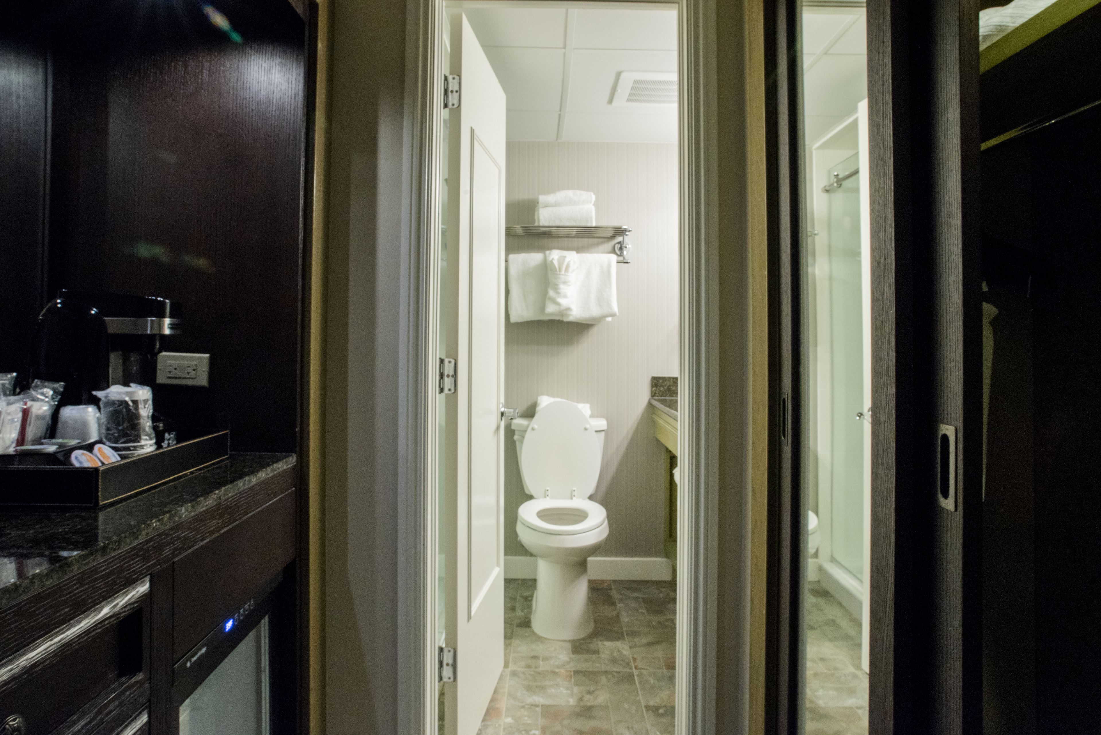 A bathroom with a toilet, a towel rack, and a shower area.