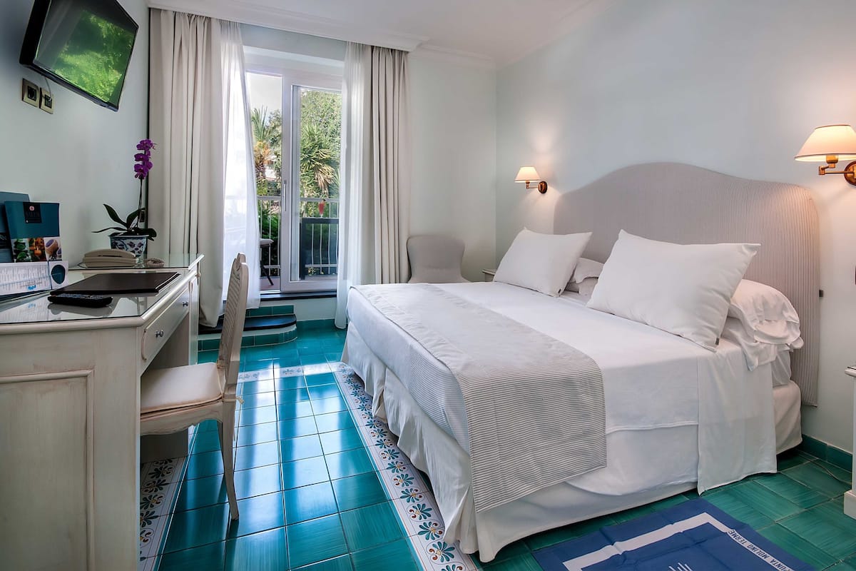 Une chambre d’hôtel équipée d’un lit, d’un bureau, d’une chaise et d’un téléviseur fixé au mur.