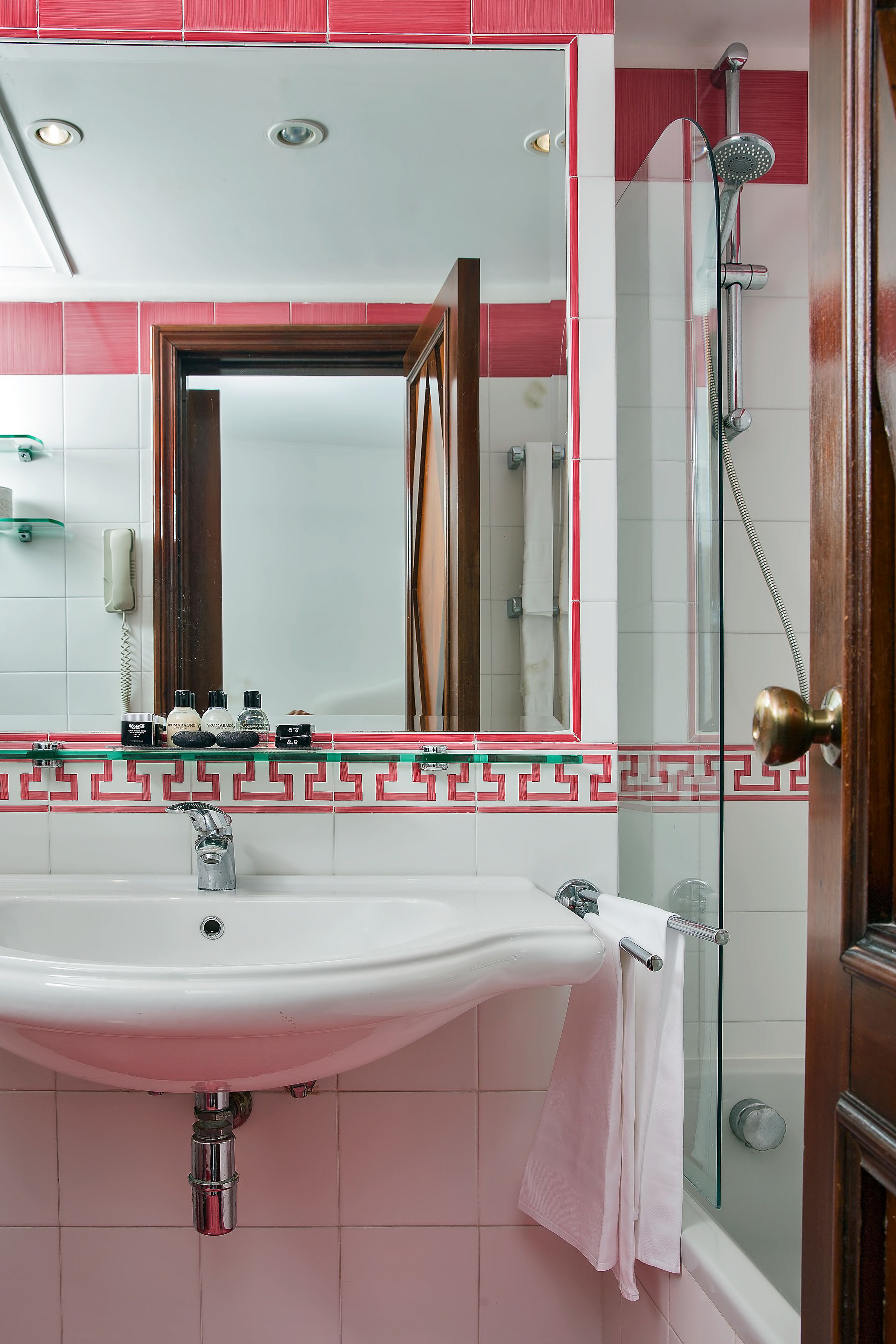 A bathroom with a sink, mirror, and shower.