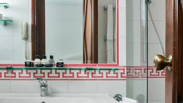 A bathroom with a sink, mirror, and shower.