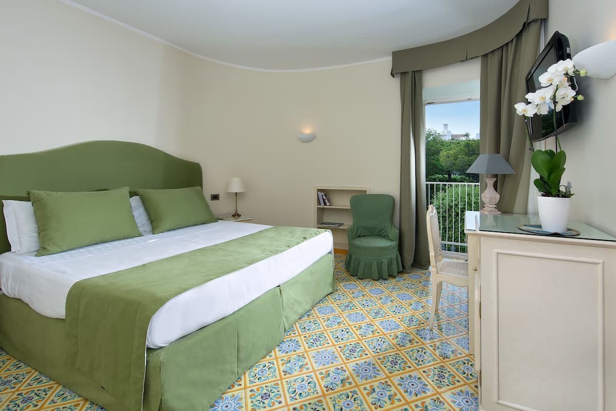 Une chambre d’hôtel avec un lit, une chaise, un bureau, une télévision et un balcon avec vue.