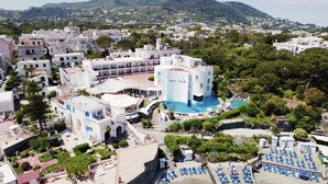 A hotel with a central pool, multiple balconies, and a surrounding garden.