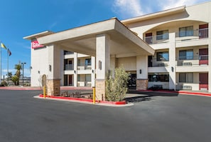 A hotel with a covered parking area, multiple balconies, and a clear sky.