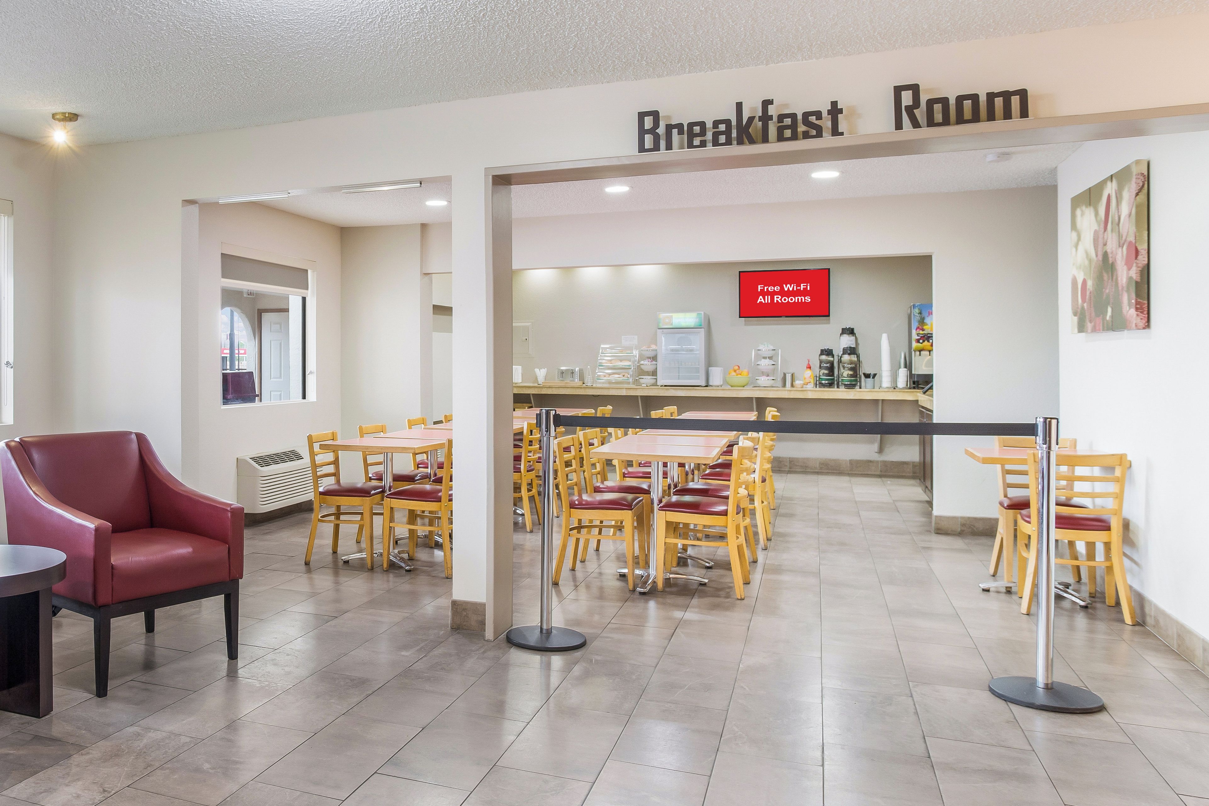 Un comedor con mesas y sillas, una máquina de café y un cartel que indica acceso a Wi-Fi gratuito.