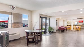 A hotel lobby with a dining area, a breakfast section, and a view of the outside.