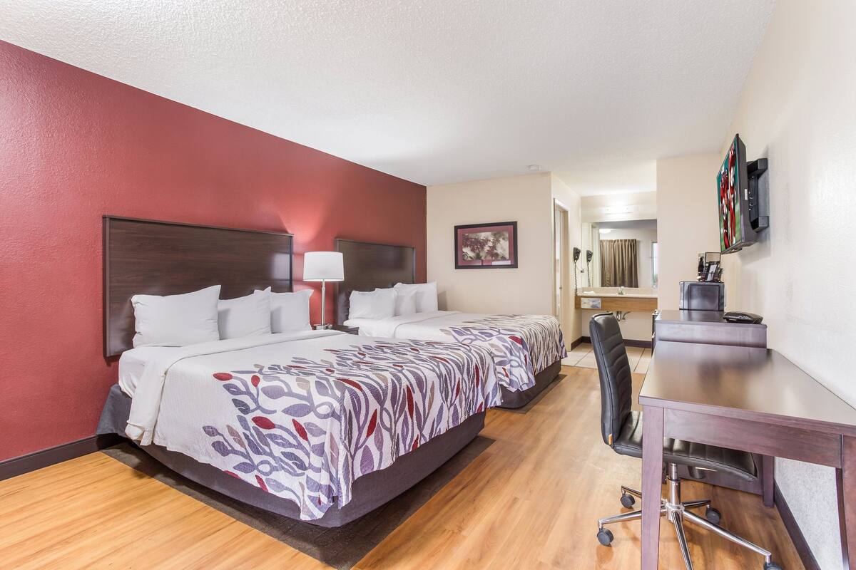 A hotel room with a large bed, a desk, a chair, and a TV.