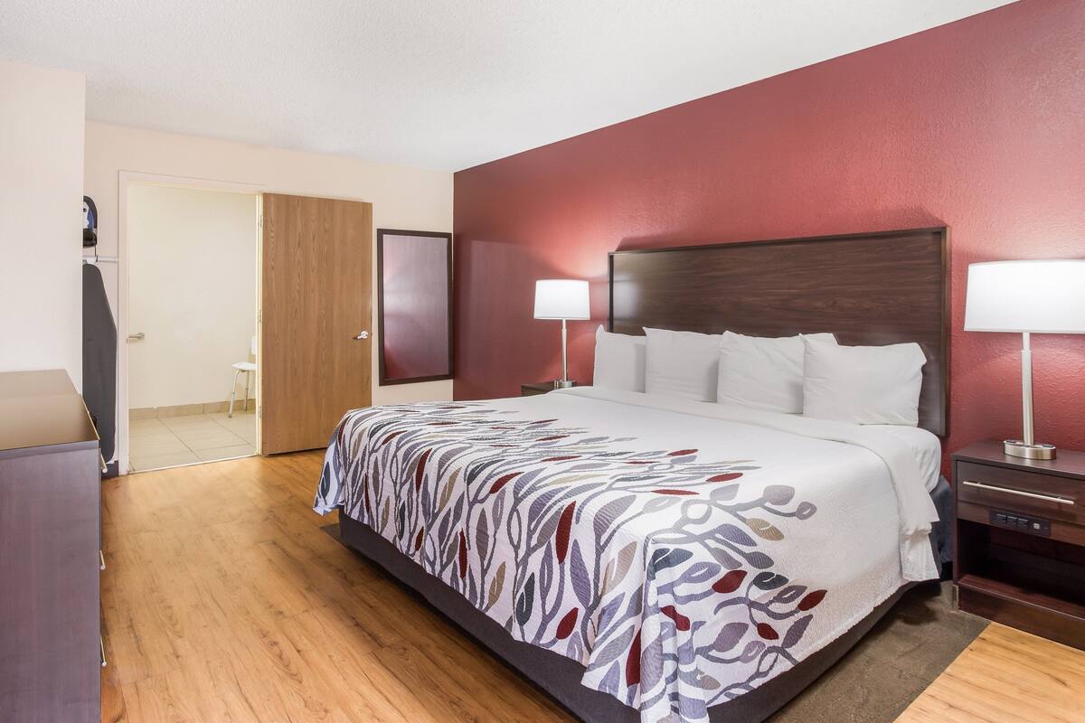 A hotel room with a large bed, wooden floor, a desk, and a chair.